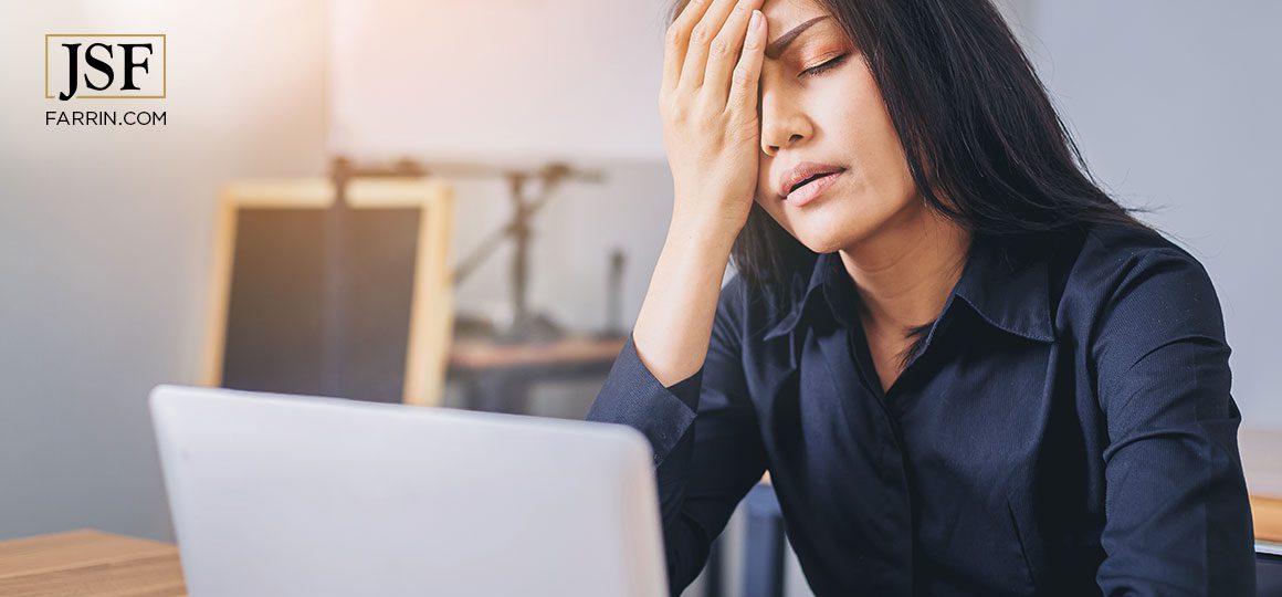 Woman rest face on hand while filling out workers' compensation info on her laptop