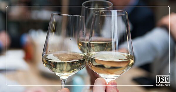 Partygoers clinking three glass flutes of champagne at a holiday celebration.