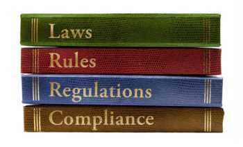  A stack of four large books titled Laws, Rules, Regulations, and Compliance.