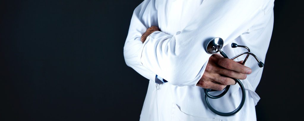 Doctor in a white lab coat with his arms crossed, holding a stethoscope.