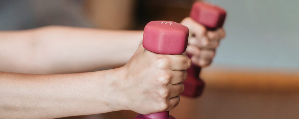 Close up of a person exercising with two hand weights.
