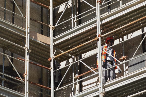 A man in high-vis gear walking on scaffolding.