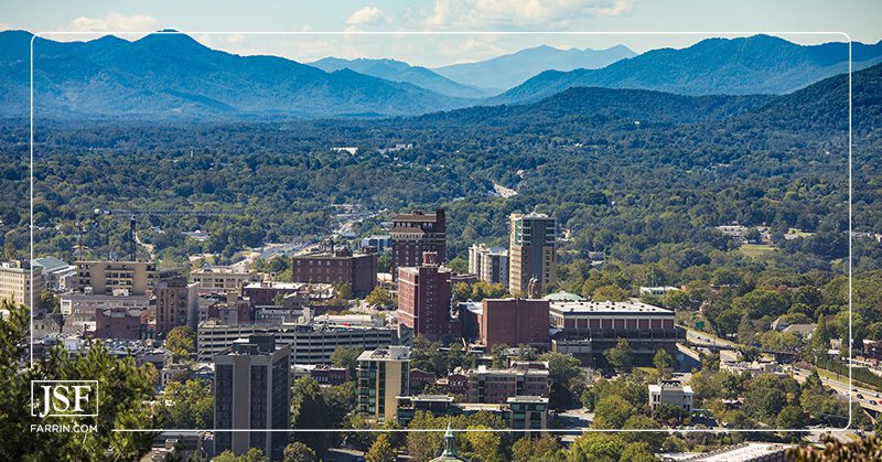 Aerial drone view of the city of Asheville, North Carolina, with the Blue Ridge Mountains in the background.