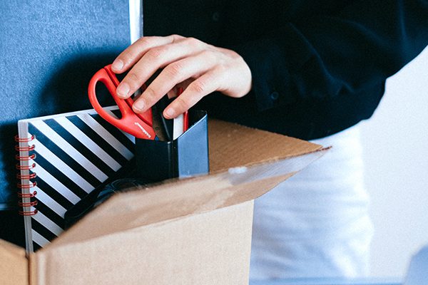 Fired employee packing up office supplies in a cardboard box