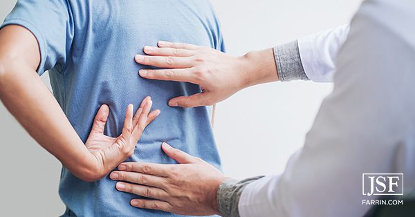A chiropractor placing their hands on a patient's back.