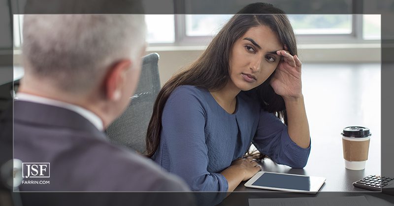 A frustrated woman holds her head in her hand during stressful negotiations with an insurance adjuster.
