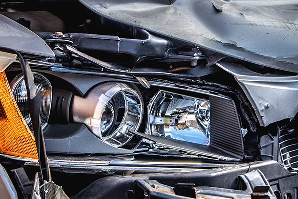Close up of a smashed car headlight and hood after an accident.