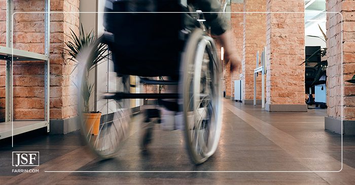 Person moving quickly on a wheelchair through brick columns in a hallway.