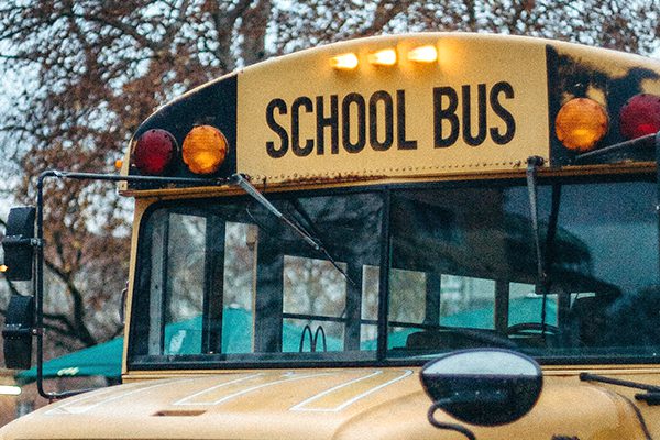 Lights and front windshield of a yellow school bus.