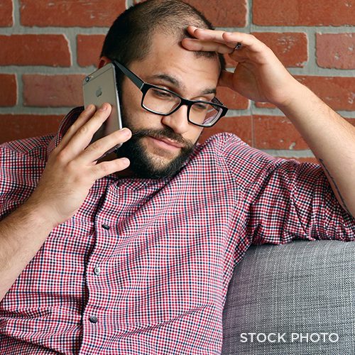 An annoyed man on the phone, with his hand on his forehead.