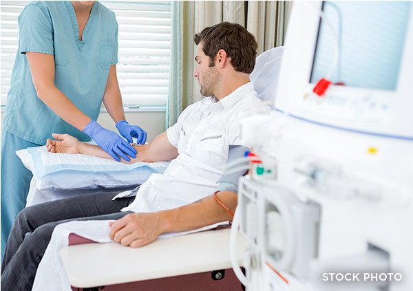 A man in a hospital ward being prepped by a nurse for kidney dialysis.