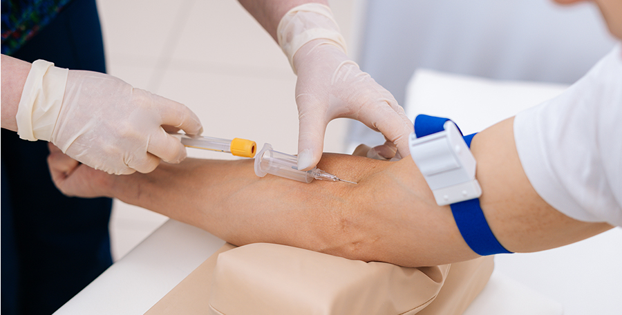 A nurse drawing blood from a patient's forearm.