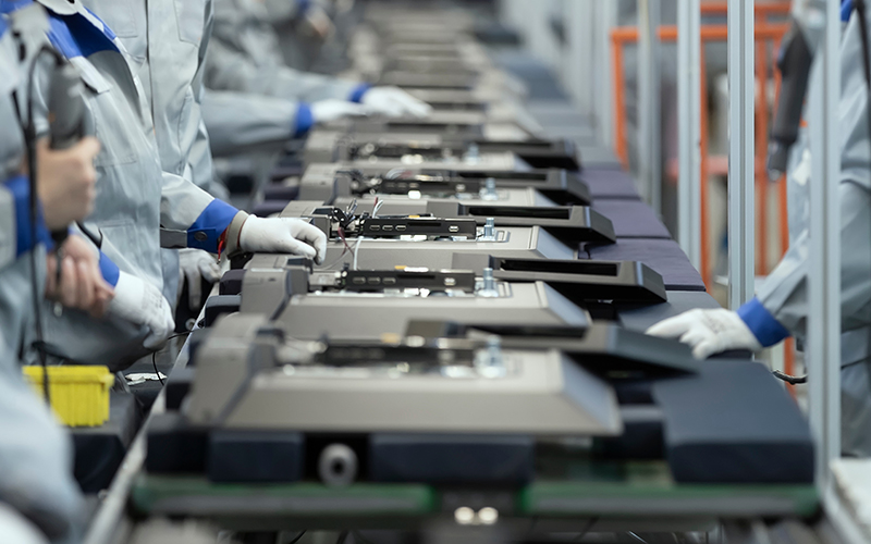 An assembly line in a manufacturing plant with people working on electronic products.