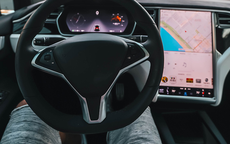 The steering wheel and dashboard of a Tesla in self-driving mode.
