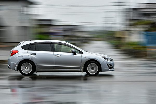 Silver car driving fast on a wet road after the rain.