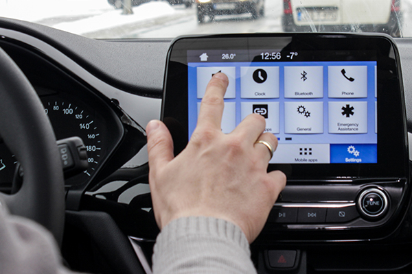 A person using the touch screen display in their car while driving.