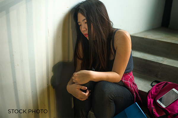 A college girl huddles in a university stairwell upset due to sex discrimination
