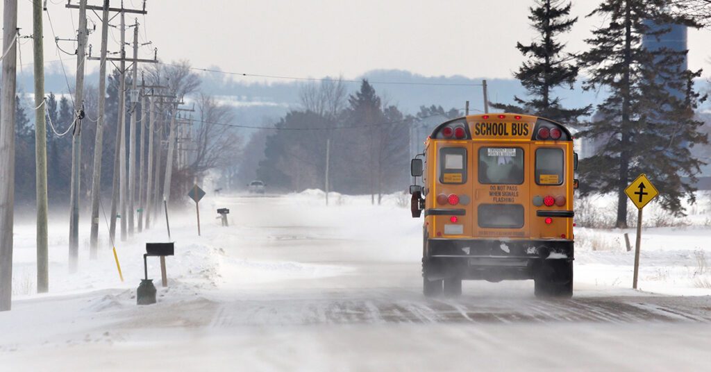 Yellow school bus driving on icy road