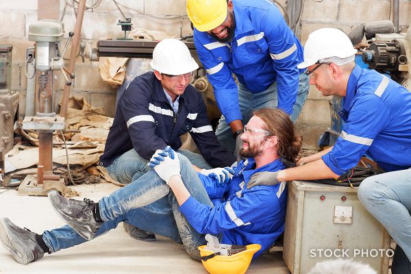 Law Offices of James Scott Farrin Greensboro NC workers’ compensation attorneys. Coworkers assist injured worker sitting on floor at job site.