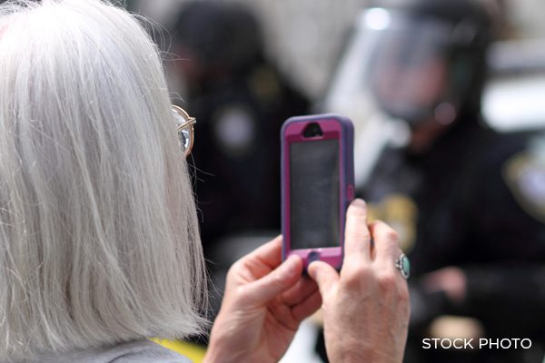 Gray-haired female films police with her phone's camera